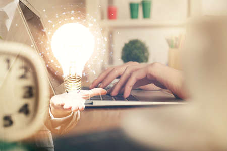 Double exposure of woman hands typing on computer and light bulb drawing. Idea concept.の写真素材