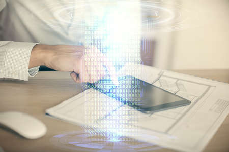 Double exposure of man's hand holding and using a digital device and data theme hologram drawing....