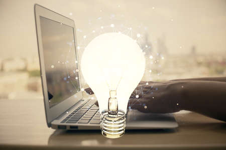 Double exposure of woman hands typing on computer and light bulb drawing. Idea concept.の写真素材