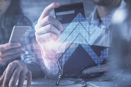 Double exposure of man and woman on-line shopping holding a credit card and arrows hologram drawing....