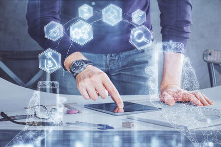 Double exposure of man's hands holding and using a digital device and tech theme hologram drawing....