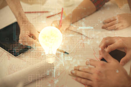 Double exposure of bulb hologram and man and woman working together holding and using a mobile device. Idea conceptの写真素材