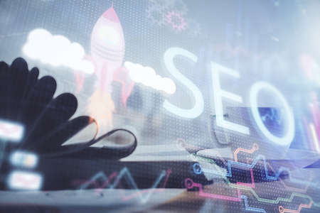 Double exposure of SEO writing and desktop with coffee and items on table background. Concept of...