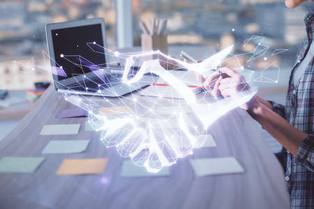 Double exposure of woman hands typing on computer and handshake drawing. Partnership concept.の写真素材