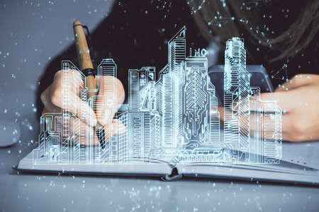 Double exposure of woman hands typing on computer and buildings drawing. Smart-city concept.の写真素材