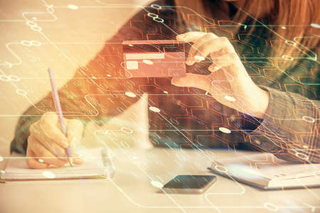 Double exposure of woman on-line shopping holding a credit card and data theme hologram drawing....