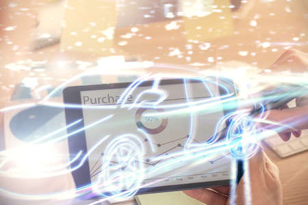 Double exposure of man's hands holding and using a digital device and automobile theme hologram...