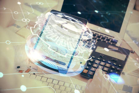 Double exposure of man's hand holding and using a digital device and data theme hologram drawing....