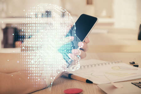 Double exposure of man's hand holding and using a digital device and brain hologram drawing. Data...