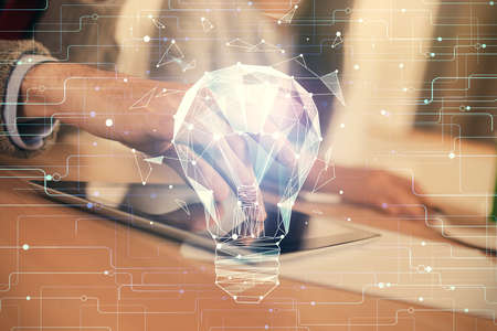 Double exposure of bulb hologram and man and woman working together holding and using a mobile...
