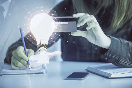 Multi exposure of woman on-line shopping holding a credit card and bulb drawing. Choice concept.の写真素材