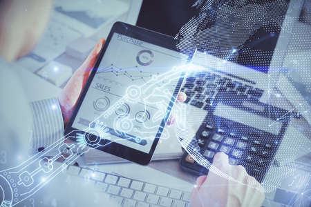 Double exposure of man's hands holding and using a digital device and tech theme hologram drawing. Technology concept.の写真素材