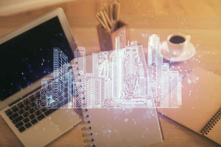 Double exposure of woman hands typing on computer and buildings drawing. Smart-city concept.の写真素材