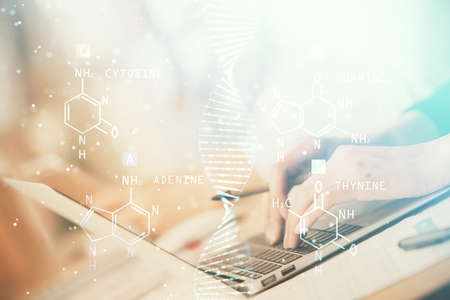 Double exposure of woman hands typing on computer and DNA hologram drawing. Medical education concept.の写真素材