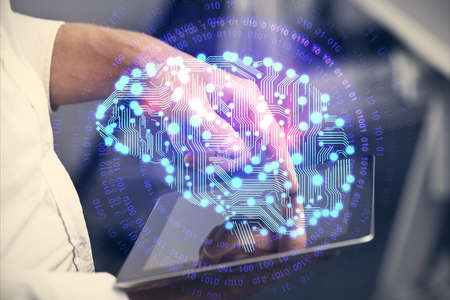 Double exposure of man's hand holding and using a digital device and brain hologram drawing. Data...