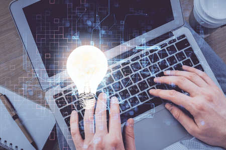 Double exposure of man's hands typing over computer keyboard and bulb hologram drawing. Top view. Idea concept.の写真素材