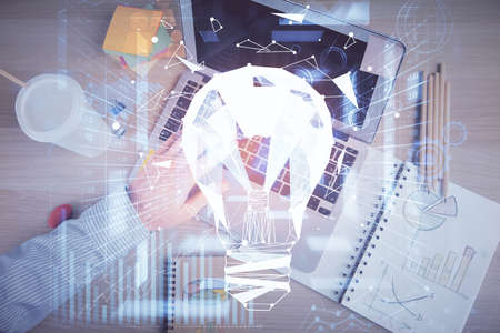 Double exposure of man's hands typing over computer keyboard and bulb hologram drawing. Top view....