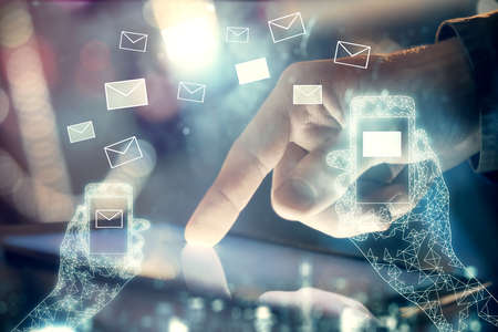 Double exposure of man's hands holding and using a digital device and envelop hologram drawing....