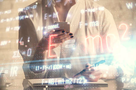Double exposure of formulas sketch hologram and woman holding and using a mobile device. Education...