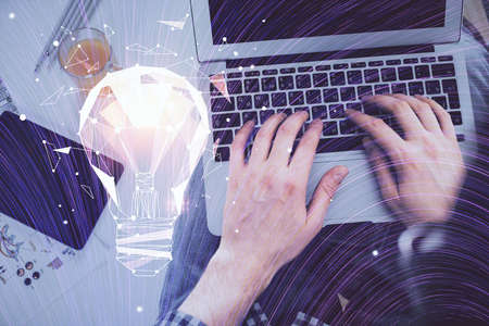 Double exposure of man's hands typing over computer keyboard and bulb hologram drawing. Top view....
