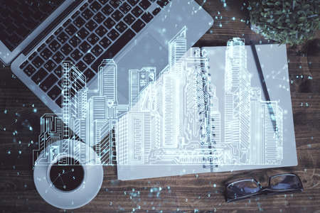 City drawing over computer on the desktop background. Top view. Double exposure. Smart home concept.