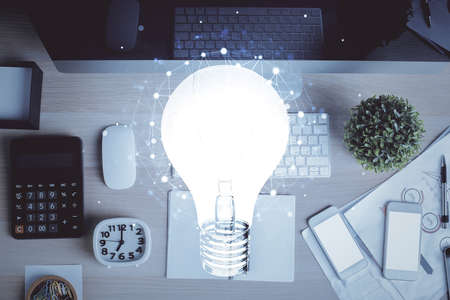 Bulb drawing over computer on the desktop background. Top view. Double exposure. Idea concept.