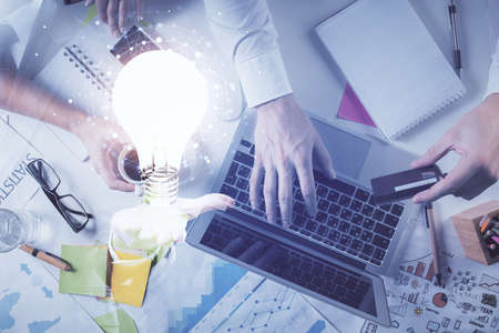 Double exposure of man's hands typing over computer keyboard and bulb hologram drawing. Top view....