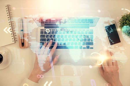 Double exposure of woman hands working on computer and world map hologram drawing. Top View....