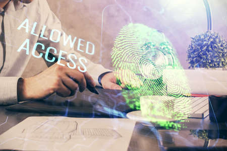 Double exposure of man's hands holding and using a digital device and fingerprint hologram drawing....