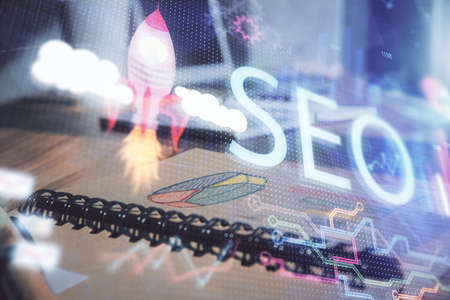 Multi exposure of SEO drawings and desk with open notebook background. Concept of Search optimizationの写真素材
