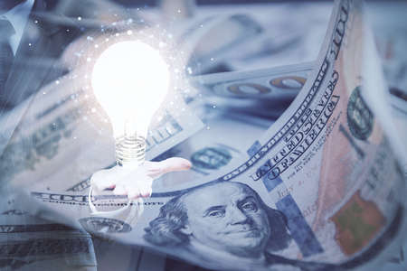 Double exposure of light bulb drawing over usa dollars bill background. Concept of idea.の写真素材