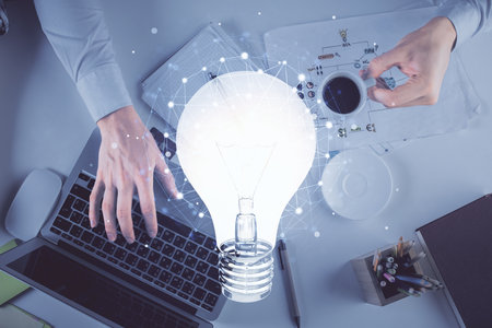 Double exposure of man's hands typing over computer keyboard and bulb hologram drawing. Top view. Idea concept.の写真素材