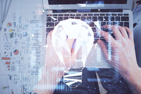 Double exposure of man's hands typing over computer keyboard and bulb hologram drawing. Top view. Idea concept.の写真素材