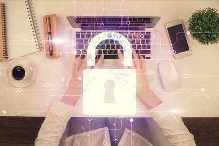 Double exposure of woman hands working on computer and lock hologram drawing. Top View. Security...
