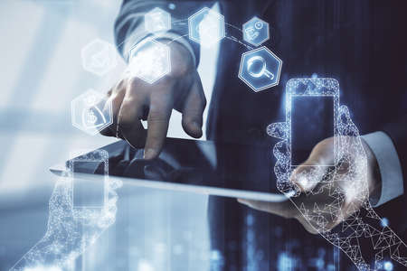 Double exposure of man's hands holding and using a digital device and tech theme hologram drawing....