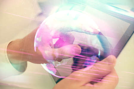 Double exposure of man's hands holding and using a digital device and tech theme hologram drawing. Technology concept.の写真素材