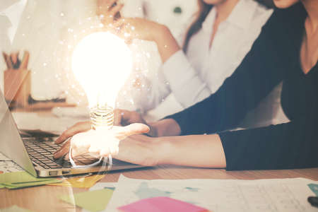 Double exposure of woman hands typing on computer and light bulb drawing. Idea concept.の写真素材