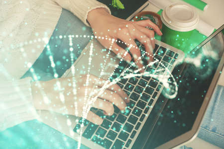 Double exposure of woman hands typing on computer and DNA hologram drawing. Medical education concept.の写真素材