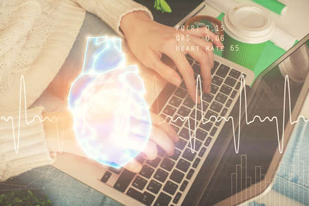 Double exposure of woman hands typing on computer and heart hologram drawing. Education concept.