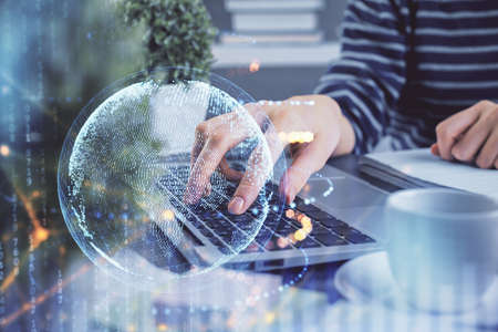 Double exposure of woman hands working on computer and world map hologram drawing. International...