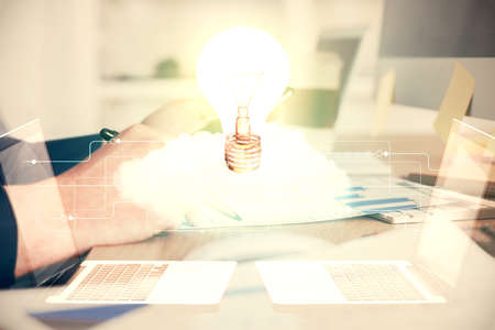 Double exposure of man's hands holding and using a digital device and bulb hologram drawing. Idea concept.の写真素材