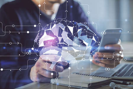 Double exposure of man's hand holding and using a digital device and brain hologram drawing. Data...