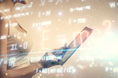 Double exposure of formulas sketch hologram and woman holding and using a mobile device. Education concept.の写真素材