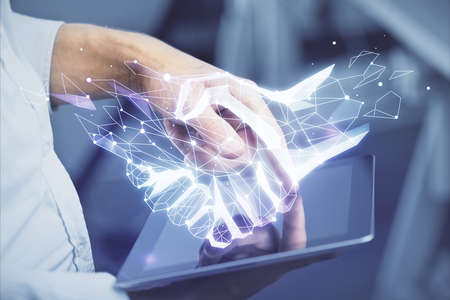 Double exposure of man's hands holding and using a digital device and handshake drawing. Partnership concept.の写真素材