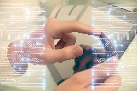 Double exposure of man's hands holding and using a digital device and tech theme hologram drawing. Technology concept.の写真素材