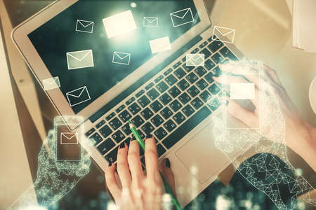 Double exposure of woman hands working on computer and envelop hologram drawing. Top View. E-mail concept.の写真素材