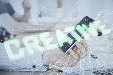Double exposure of man's hands holding and using a mobile device and creative hologram drawing.の写真素材