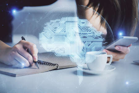 Double exposure of brain sketch hologram and woman holding and using a mobile device.