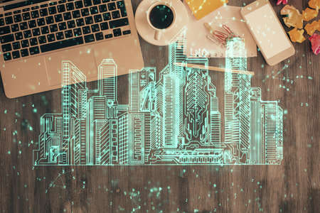 City drawing over computer on the desktop background. Top view. Double exposure. Smart home concept.