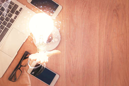 Double exposure of bulb drawing over table with phone. Top view. Concept of idea.の写真素材